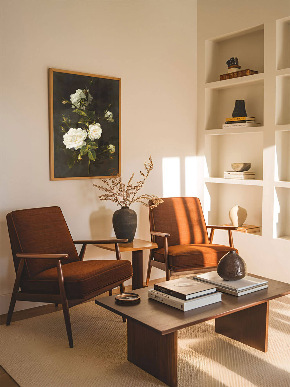 Barockes Stillleben mit einer weißen Rose und zarten Knospen, eingerahmt und aufgehängt in einem gemütlichen Wohnzimmer. Zwei Mid-Century-Sessel aus warmem Holz und orangefarbenem Stoff stehen vor einem modernen Couchtisch.