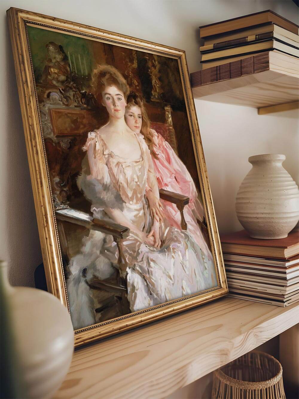 Nahaufnahme eines viktorianischen Porträts zweier Frauen im kunstvollen, goldenen Rahmen, platziert auf einem Regal mit dekorativen Büchern und Vasen. Das Gemälde bringt Eleganz in die Wohnraumdekoration.