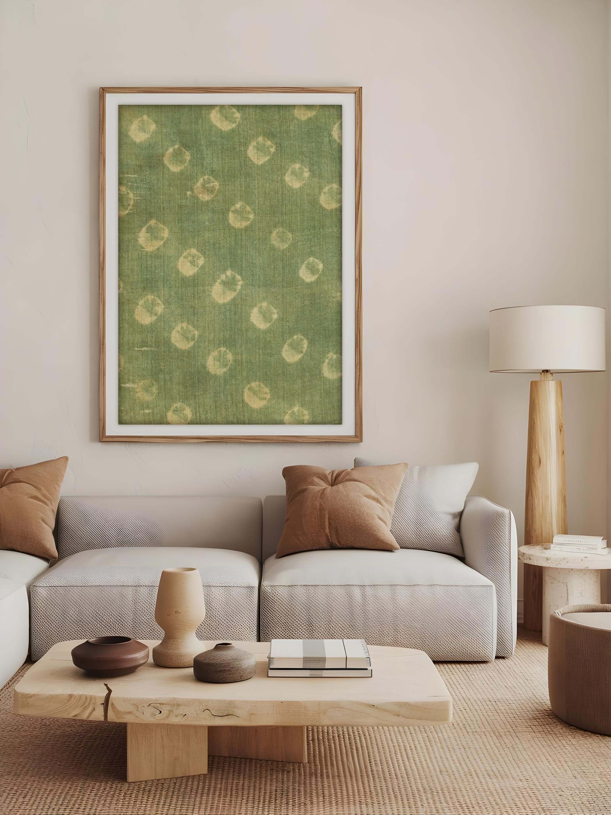 Großes Wabi-Sabi Poster mit grünem Stoff-Fragment, eingerahmt in einem hellen Holzrahmen, hängt über einem modernen Sofa in einem minimalistischen Wohnzimmer mit natürlichen Farbtönen.